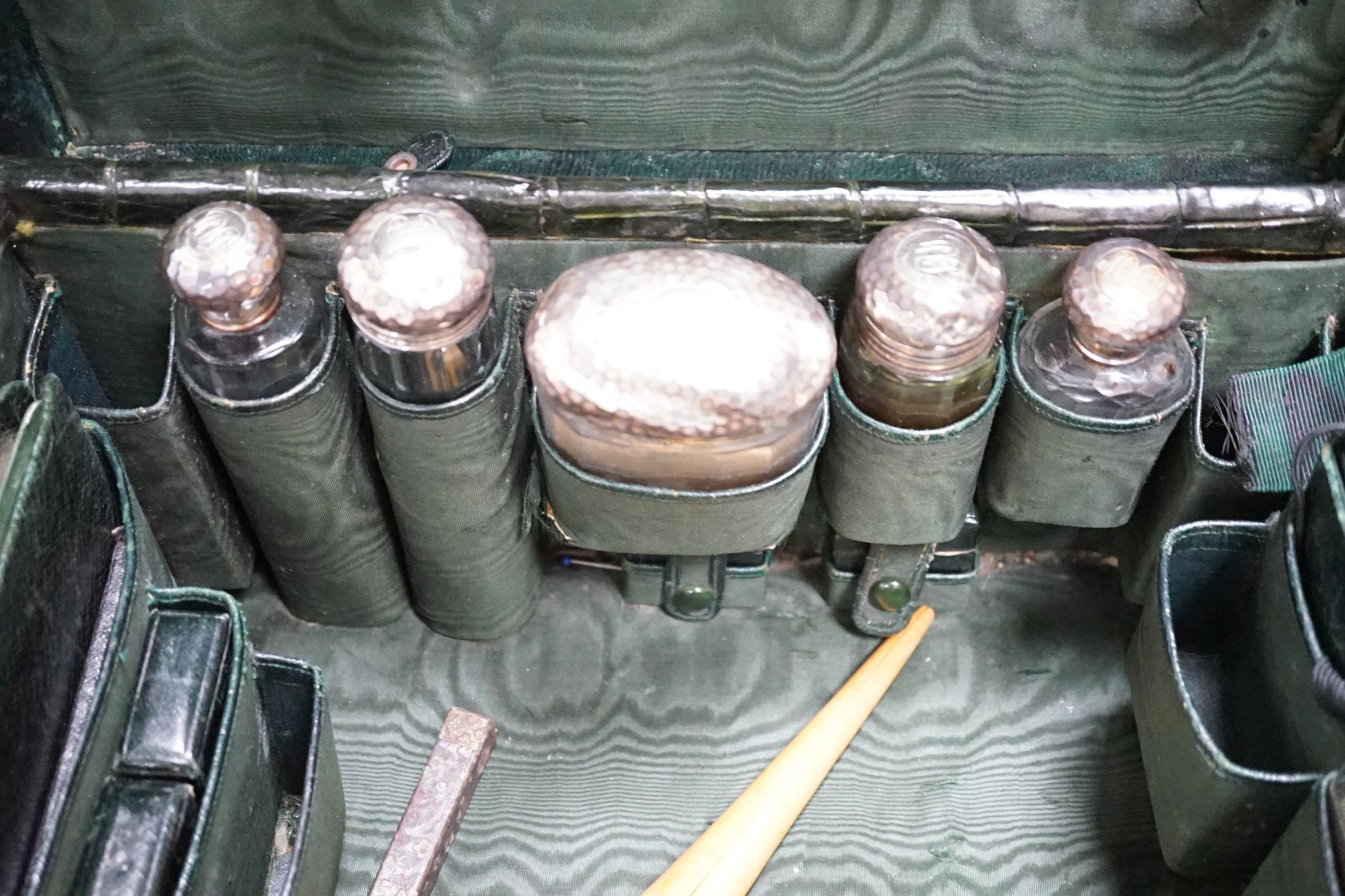 An early 20th century green crocodile toilet case with silver mounted interior, width 39 cms.